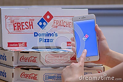 Close up of a person using the Dominoâ€™s Pizza application on an iPhone Plus. Dominoâ€™s Pizza Editorial Stock Photo